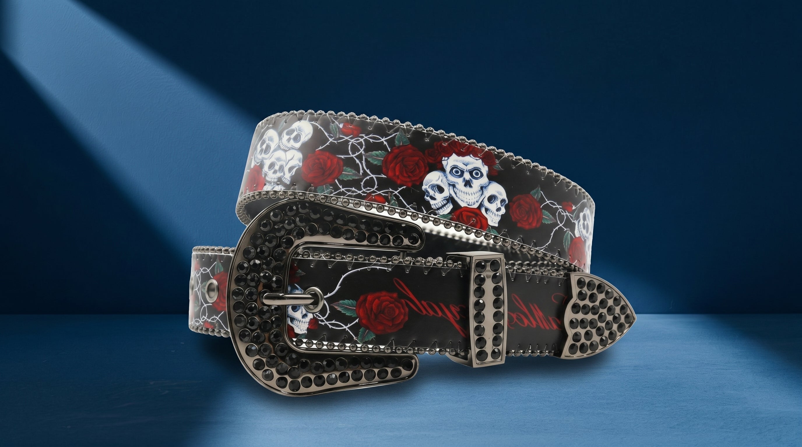 Ceinture homme à boucle western avec pierres noires, motif crânes et roses rouges sur fond bleu.