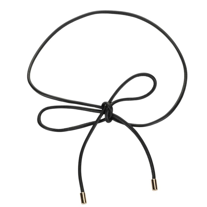 Ceinture fine noire Amicie en cuir pleine fleur avec extrémités dorées, nouée en forme de nœud décoratif.