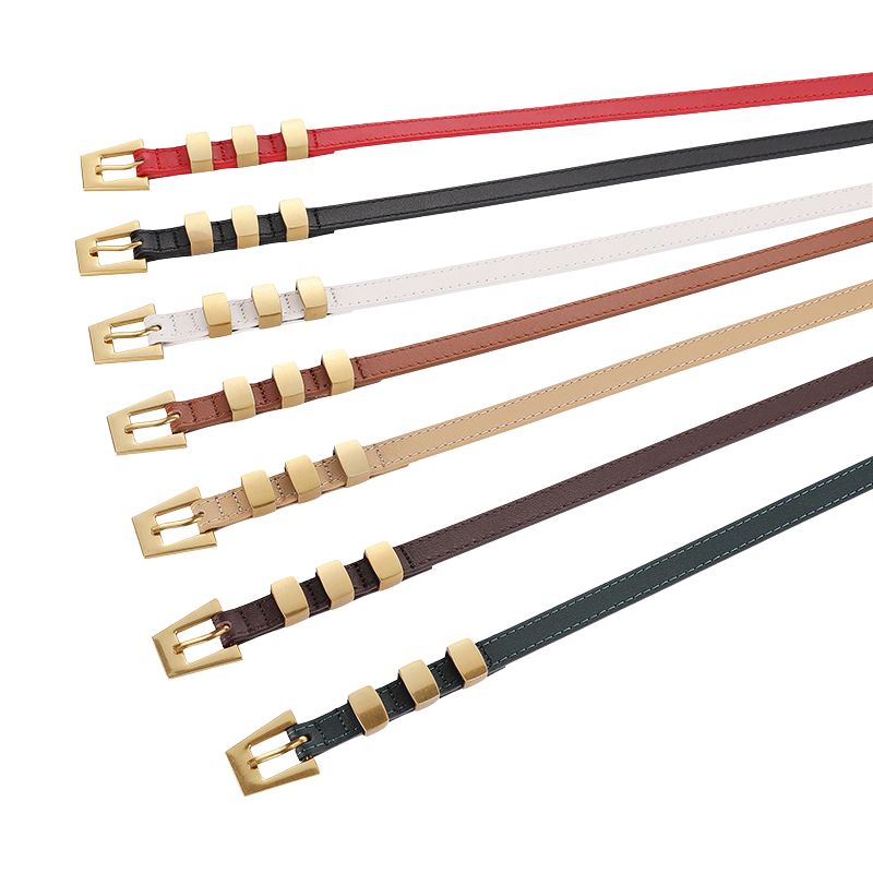 Collection de ceintures fines Béatrice en cuir nubuck, disponibles en rouge, noir, blanc, marron clair, beige, marron foncé et vert sapin, ornées de boucles ardillon triangulaires dorées.