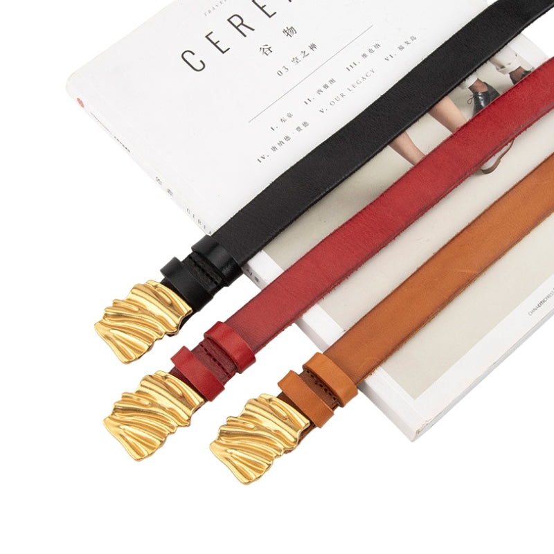 Trois ceintures pour femme Caresseuse en cuir pleine fleur, une noire, une rouge et une couleur chameau, chacune dotée d'une boucle asymétrique en métal doré avec un effet plissé texturé.