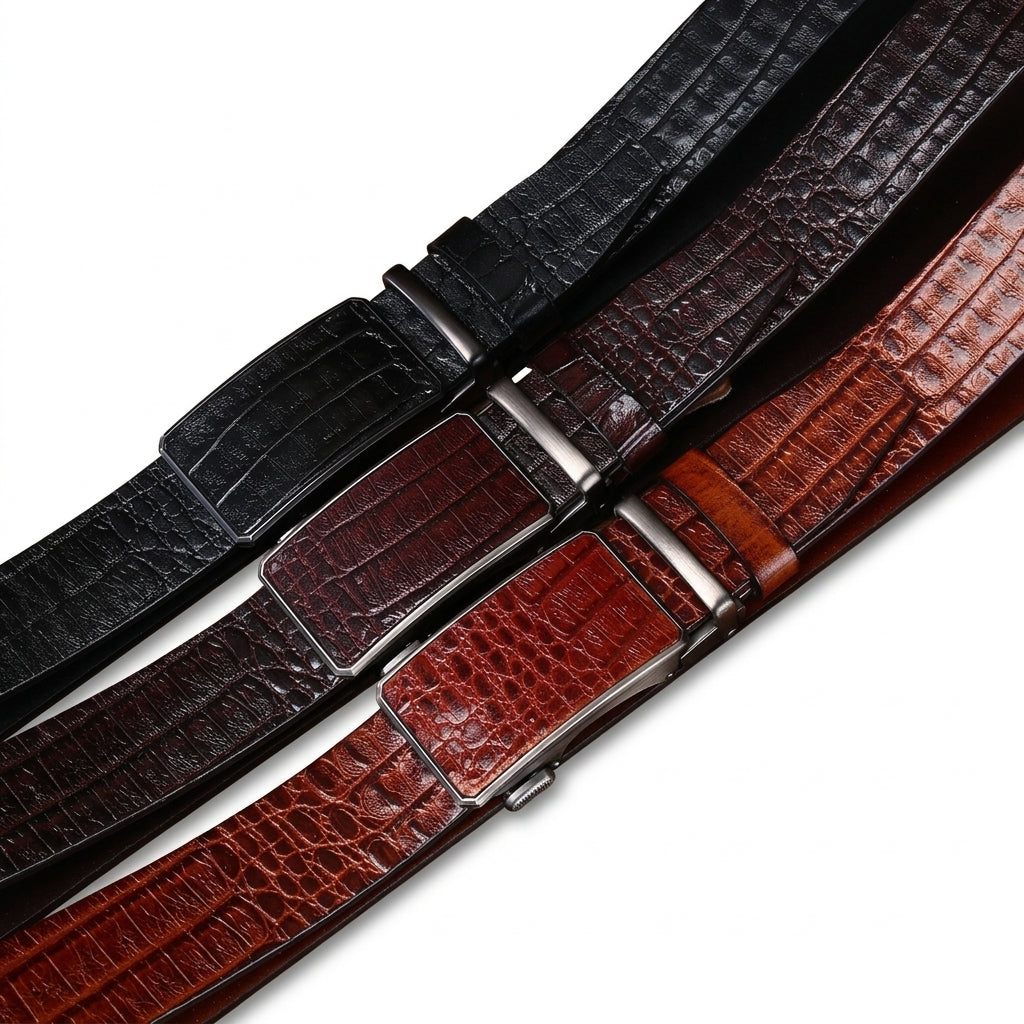 Trois ceintures Castiglione en cuir pleine fleur de vachette avec motif crocodile gaufré, disponibles en noir, marron foncé et cognac, équipées de boucles automatiques rectangulaires argentées.
