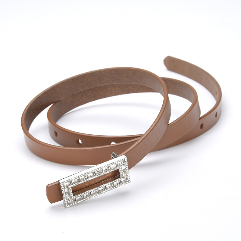 Ceinture fine pour femme Clarisse en cuir marron lisse avec une boucle ardillon rectangulaire ornée de strass scintillants sur fond blanc