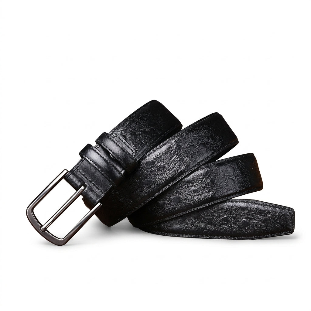 Ceinture homme Valmy en cuir pleine fleur noir avec motif autruche en relief et boucle ardillon argentée posée sur une table en bois, fond sombre