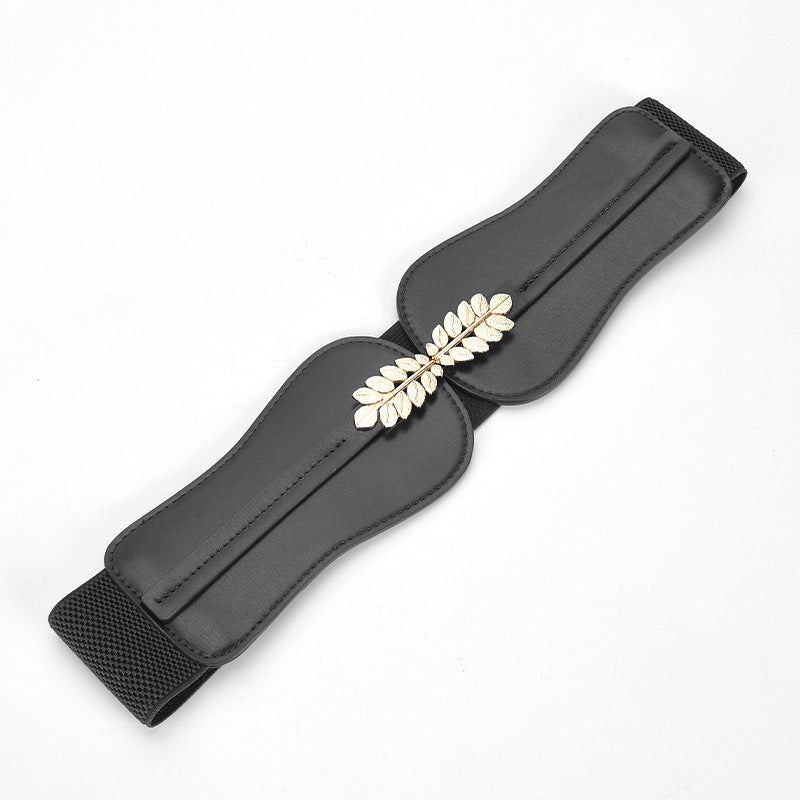 Ceinture large noire pour femme Mélisande en cuir pleine fleur avec boucle décorative dorée en forme de feuilles sur fond blanc
