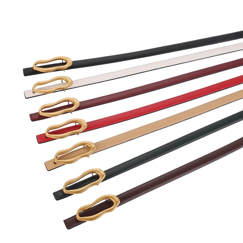 Ceinture fine Nadège en cuir pleine fleur de vachette, disponible en plusieurs couleurs (noir, blanc, bordeaux, rouge, beige, vert foncé, marron) avec boucle dorée ovale asymétrique.