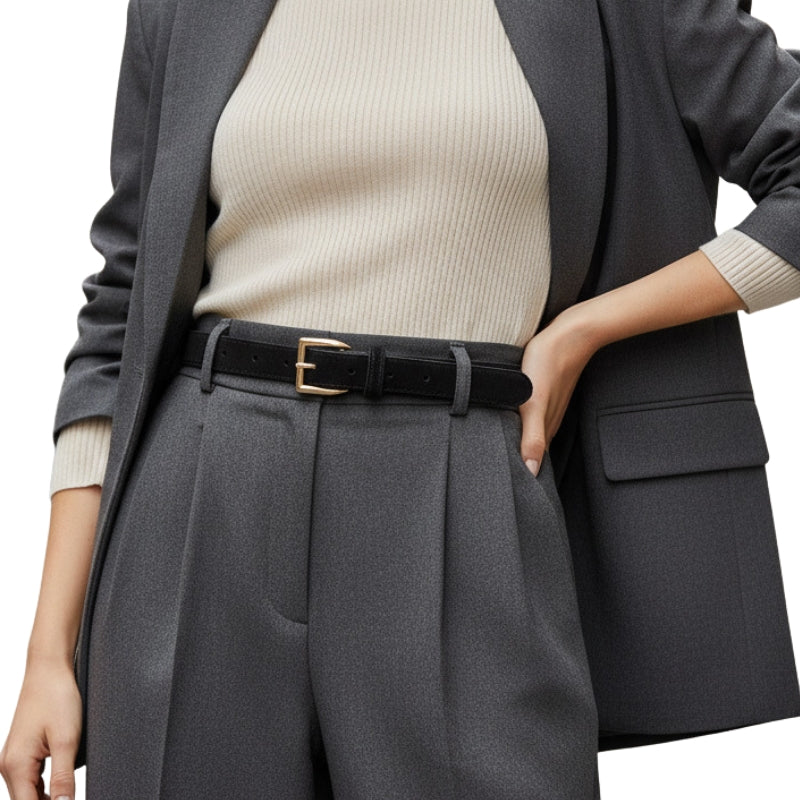 Ceinture femme Virtuose noire en cuir de vachette refendu, finition daim, avec boucle rectangulaire dorée, portée avec un blazer gris et un pantalon assorti.