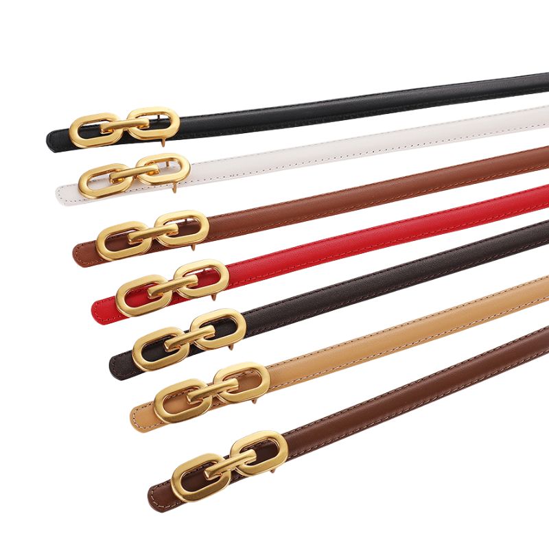 Ceinture fine Ysaline en cuir noir avec boucle dorée décorative de style chaîne, présentée avec d'autres ceintures de couleurs variées.