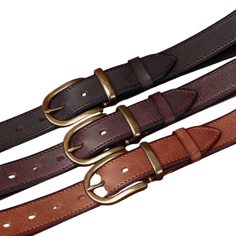 Trois ceintures en cuir Bravura Cuir de différentes couleurs (noir, marron foncé, marron clair) avec des boucles ardillon arrondies en cuivre doré, montrant la texture du cuir vieilli et tanné végétal. #fullwidth