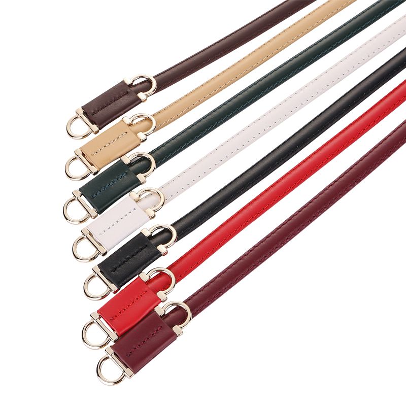 Ensemble de ceintures fines Célestine en cuir pleine fleur de vachette dans diverses couleurs : bordeaux, beige, vert foncé, blanc, noir, rouge et bordeaux foncé, chacune dotée d'une boucle D-Ring dorée décorative.