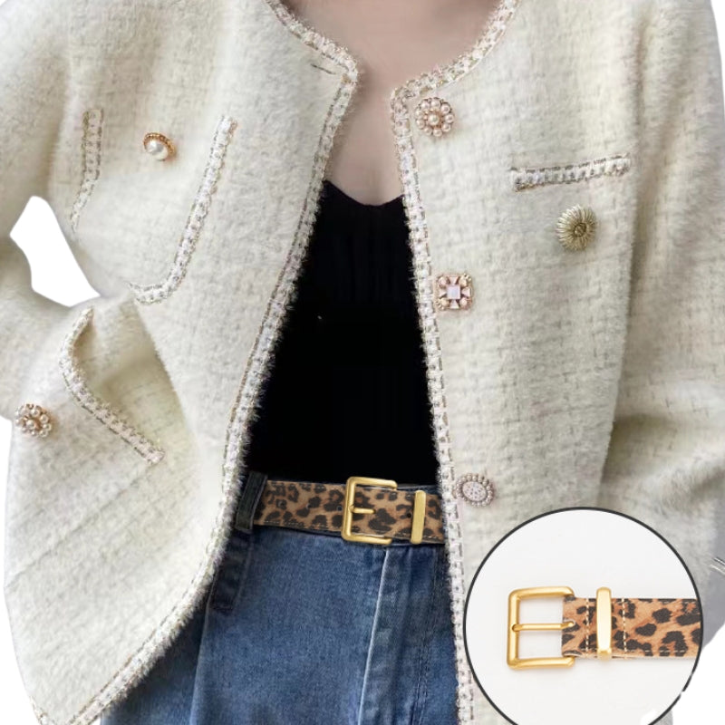 Ceinture fine en cuir avec imprimé léopard et boucle dorée, portée par-dessus un jean et une veste texturée.