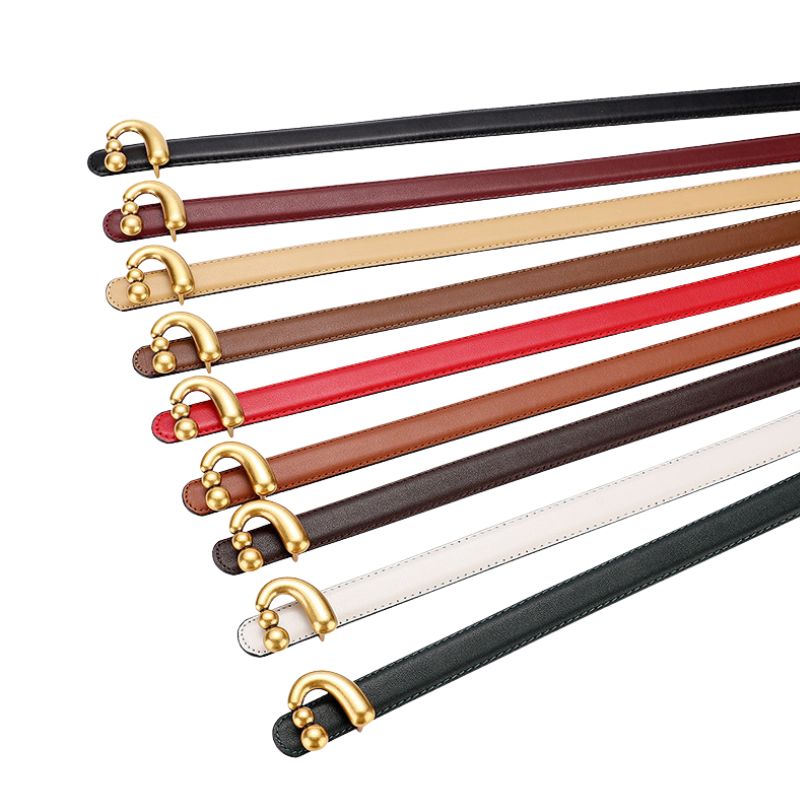 Ceinture femme Domitille en cuir disponible en plusieurs couleurs : noir, bordeaux, beige, marron clair, rouge, marron foncé, blanc et vert, avec boucle dorée asymétrique et boules décoratives.