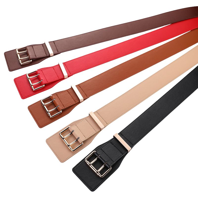 Cinq ceintures Essence larges de 6,5 cm, de différentes couleurs (marron foncé, rouge, marron clair, beige et noir), chacune dotée d'une boucle rectangulaire dorée à double ardillon.