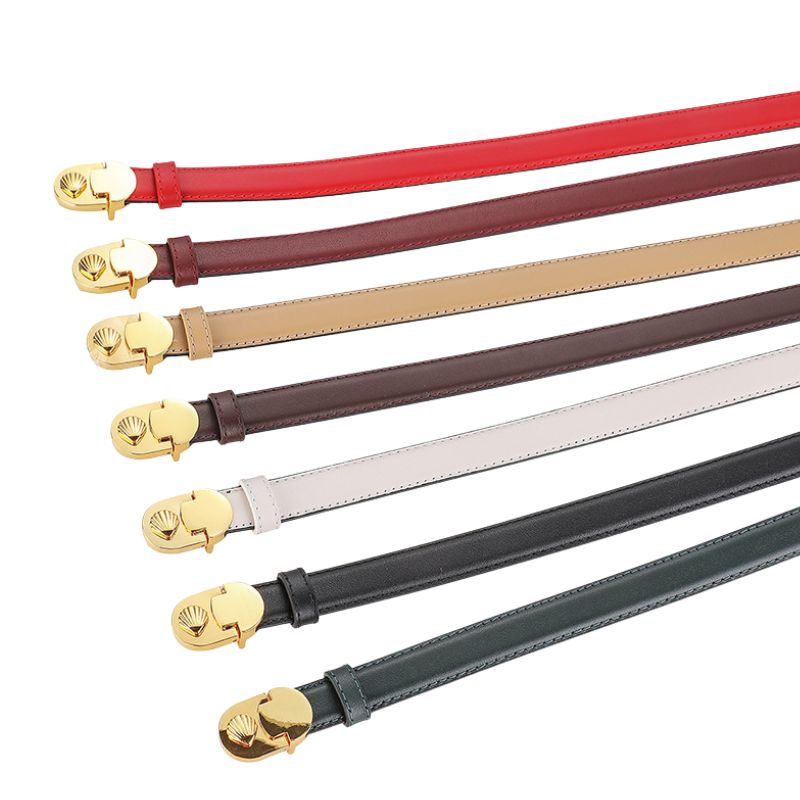 Collection de ceintures fines en cuir refendu de vachette de la marque Megève, disponibles en rouge, bordeaux, beige, marron, blanc, noir et vert, avec une boucle ovale dorée à motif coquillage.