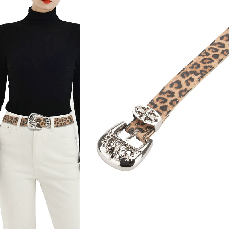 Ceinture Ophéline en cuir imprimé léopard avec boucle argentée ornée de motifs gravés, portée par une femme avec un col roulé noir et un pantalon blanc.