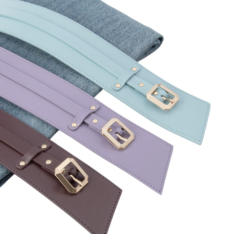 Trois ceintures larges pour femme de la marque Solène, en cuir lisse, dans des tons pastel : bleu ciel, lilas et marron. Chacune est dotée d'une boucle ardillon dorée carrée et d'une finition soignée. Elles sont présentées sur un tissu denim.