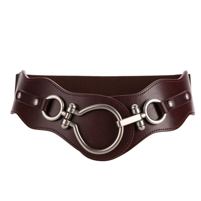 Ceinture femme Uline marron en cuir refendu finition daim, avec boucle crochet argentée style mors de cheval et design harnais. Largeur 7,5 cm.